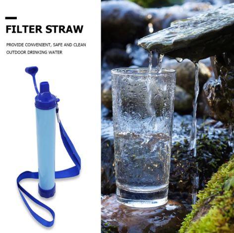 Portable filter straw and a glass being filled with fresh water from a stream outdoors